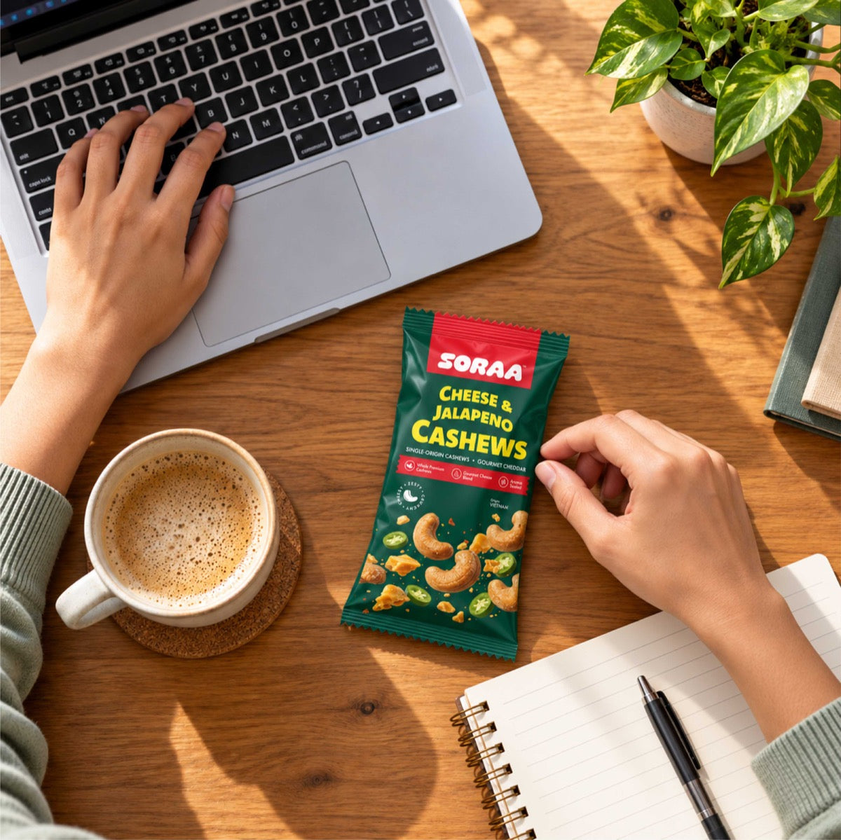 SORAA Cheese & Jalapeno Cashews beside a laptop and coffee